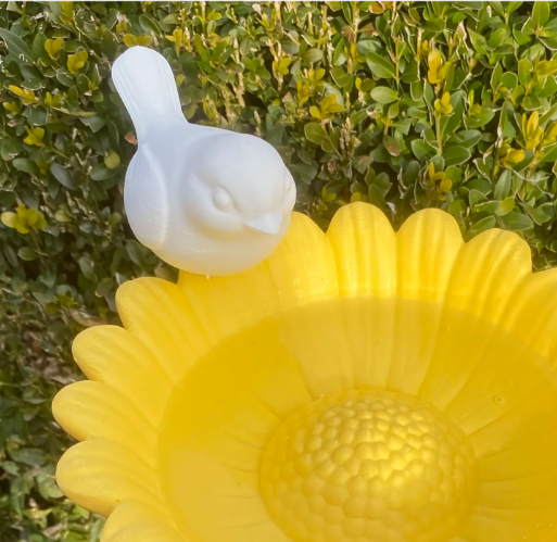 Close-up of 3D printed yellow sunflower bird bath with white bird detail