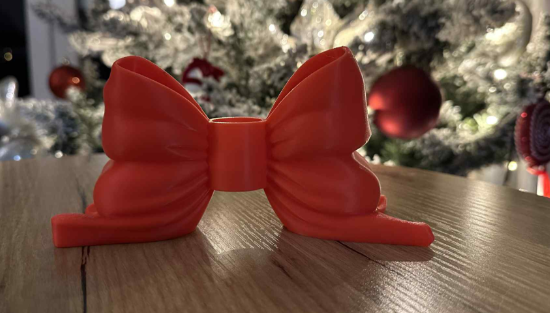 3D printed red bow candle holder side view on wooden table