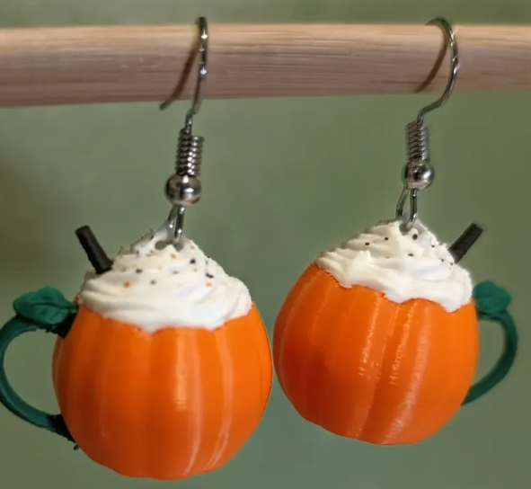3D printed pumpkin spice latte earrings hanging on rod green background