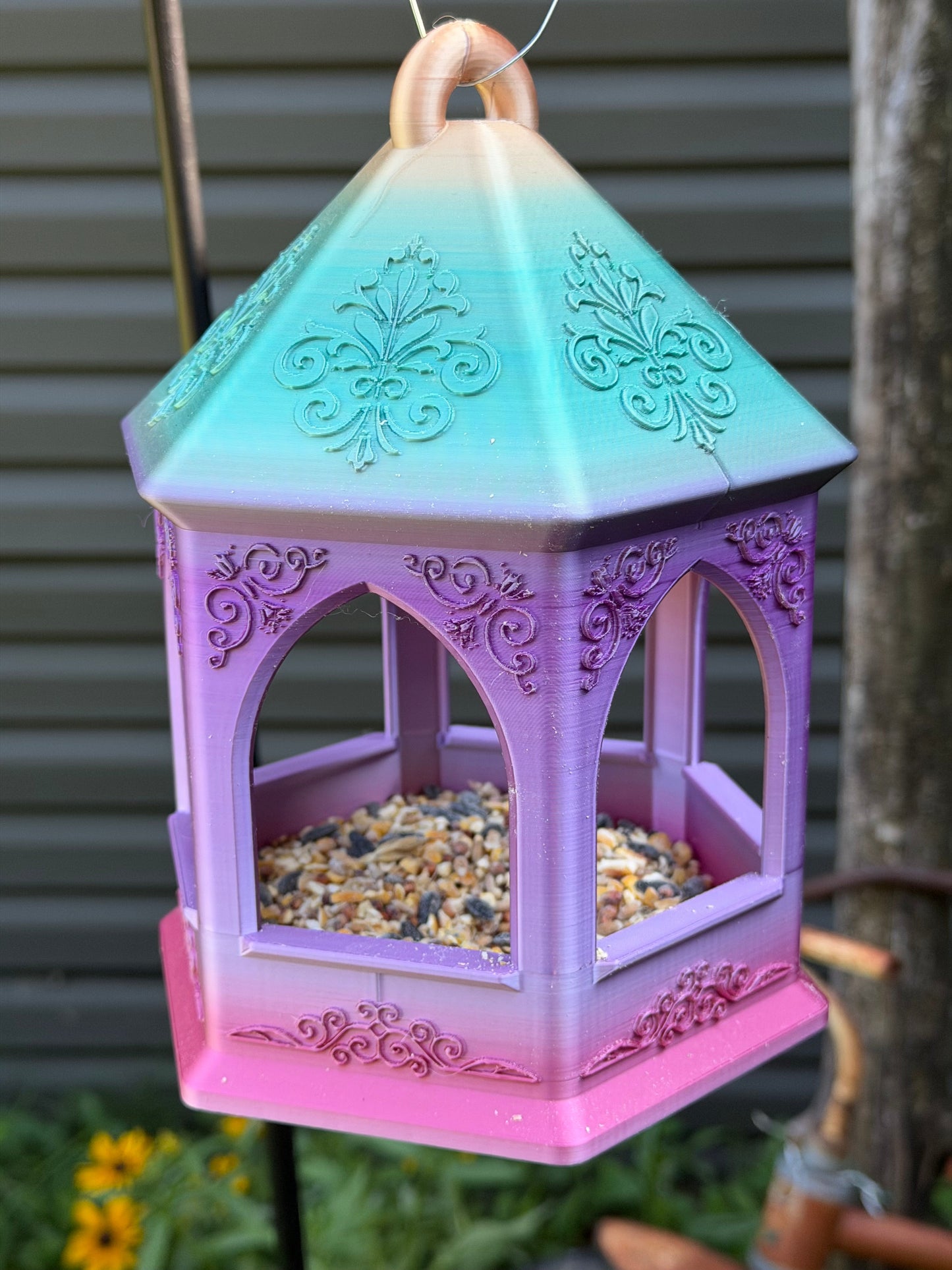 Close-up of ornate scroll and fleur-de-lis detail on bird feeder roof