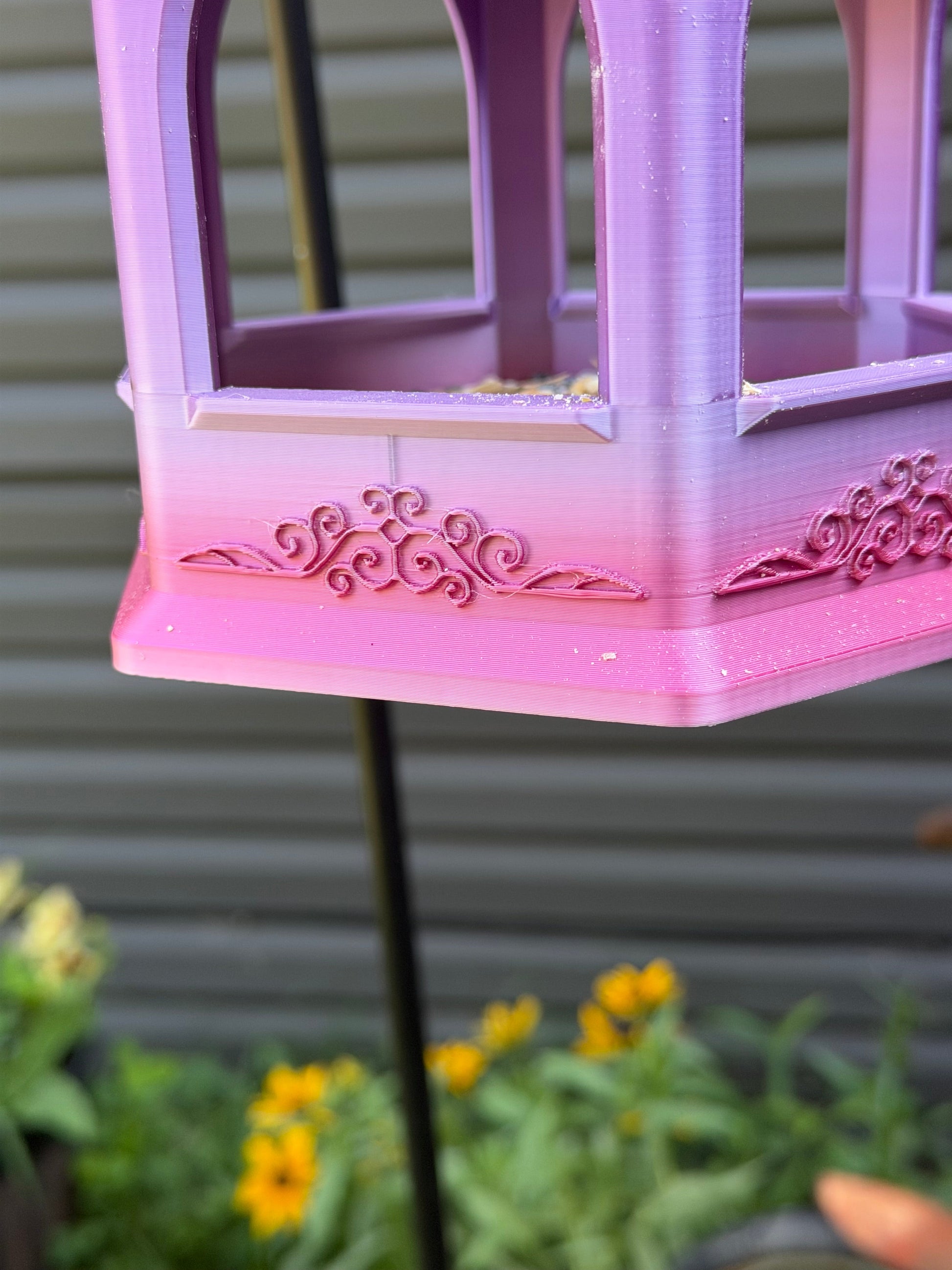 Elegant hexagonal bird feeder in garden with black-eyed Susans